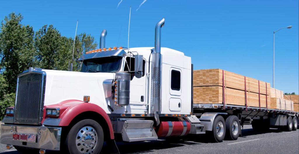 Image shows a flatbed trailer hauling planks of wood.