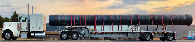 White trailer with a step deck trailer transporting a huge piece of pipe