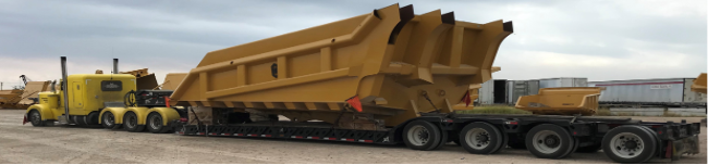 Yellow truck with a removable gooseneck hauling heavy equipment shipping