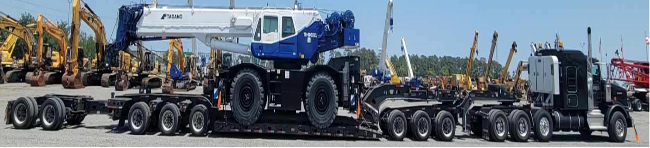 Black truck with a double drop trailer hauling heavy equipment shipping