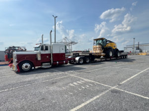 Oversized forage harvester secured to a flatbed trailer for specialized freight transport supported by Trinity Logistics Sartell, a Minnesota 3PL.