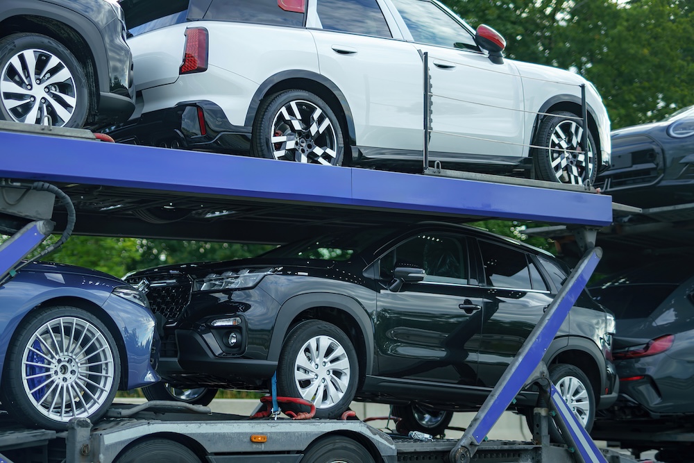 SUVs secured on an open auto transportation trailer for vehicle delivery.
