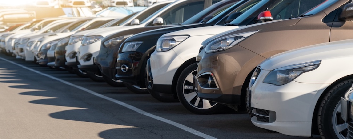 Rows of vehicles at a dealership awaiting auto transportation and delivery.